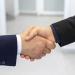 Close-up of a handshake in a business environment, symbolizing partnership.