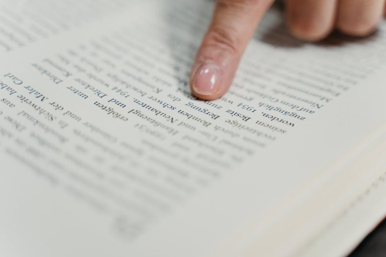 A detailed view of a finger pointing at text in a book, emphasizing reading and study.