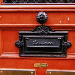 { Classic French letterbox on a red wooden door in Paris.