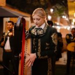 Federated Edge Orchestration: Scalable EdTech Strategy Guide Musician in traditional mariachi attire plays harp at an evening event with warm ambient lighting.