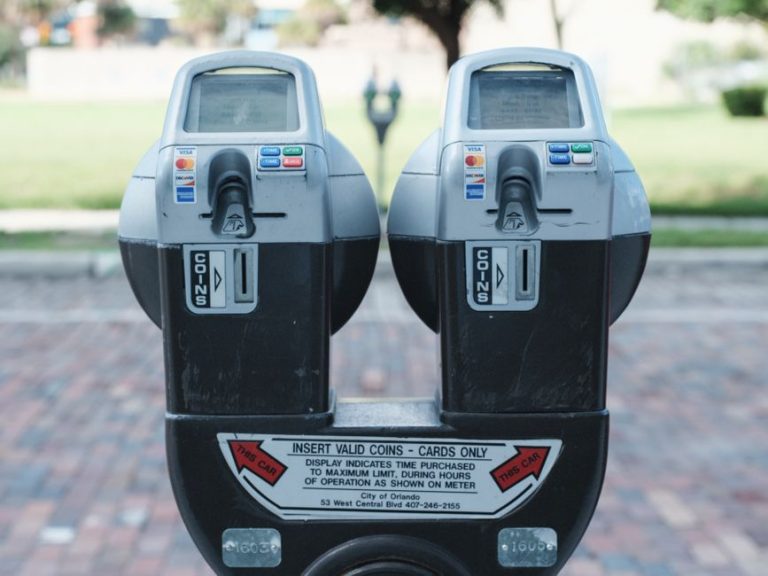 Photo of two parking meters in Orlando showing coin and card payment options on a brick road.