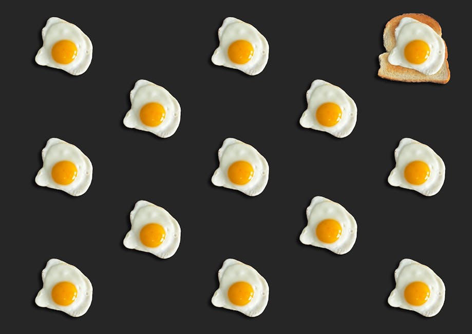 Creative pattern of fried eggs on black with toast, top view.