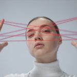 Creative portrait of a woman interacting with a red string art concept.