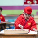 Young boy wearing glasses focused on educational activity in classroom setting.