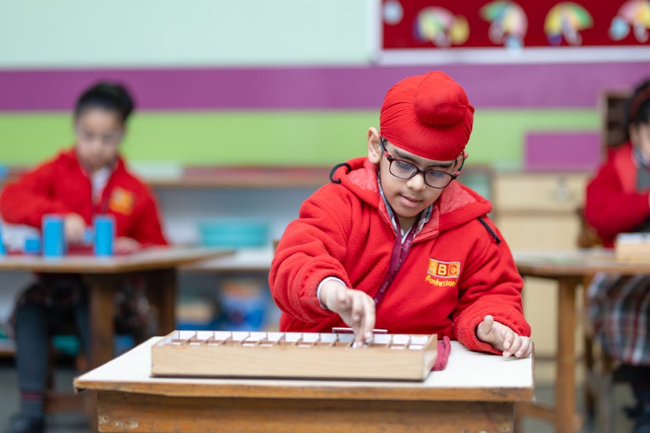 Young boy wearing glasses focused on educational activity in classroom setting.