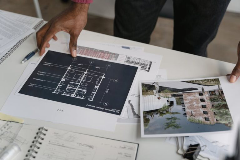 Architect hands reviewing architectural blueprints and design documents in an office setting.