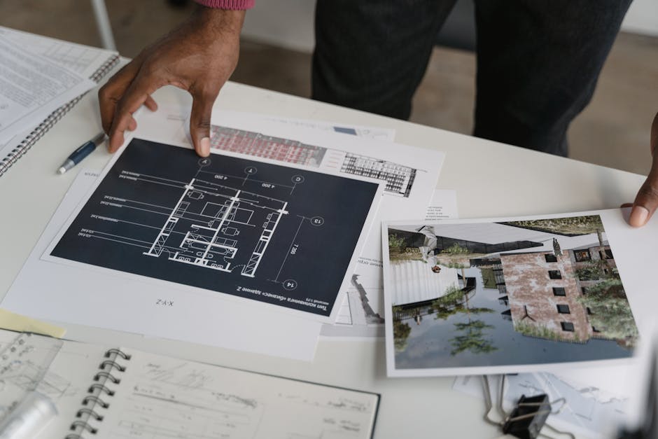 Architect hands reviewing architectural blueprints and design documents in an office setting.