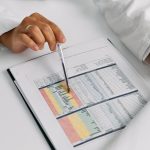 Graph-Based Hospital-at-Home Control Policies Doctor hands examining and pointing at medical charts in a close-up view.