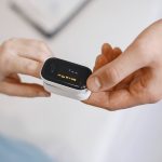Hospital-at-Home Nanotech: Sim-to-Real Healthcare Models Close-up of a pulse oximeter on a finger, checking oxygen levels during a healthcare examination.