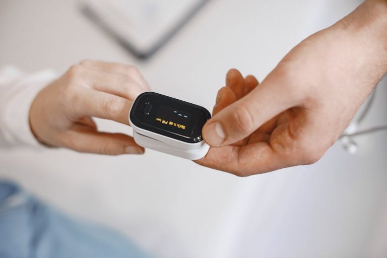 Close-up of a pulse oximeter on a finger, checking oxygen levels during a healthcare examination.