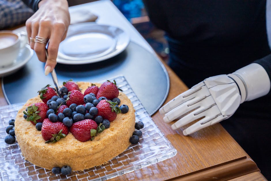 A person with a prosthetic arm cuts a cake topped with strawberries and blueberries, showcasing modern technology.