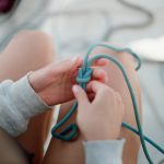 <h1>Human-In-The-Loop Causal Inference: The Future of Biotechnology R&D</h1> Detail shot of hands tying a blue rope knot, showcasing craftsmanship and technique.