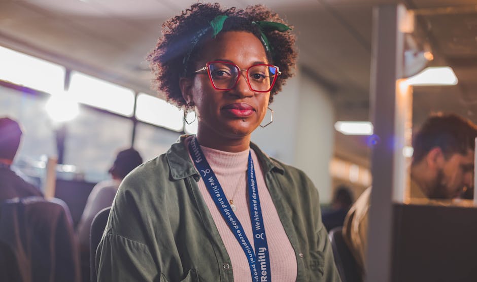 Portrait of a woman wearing red glasses in an office, showcasing confidence in a modern work environment.