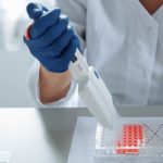 Close-up of a scientist using a pipette in a lab with a focus on sterile procedures.