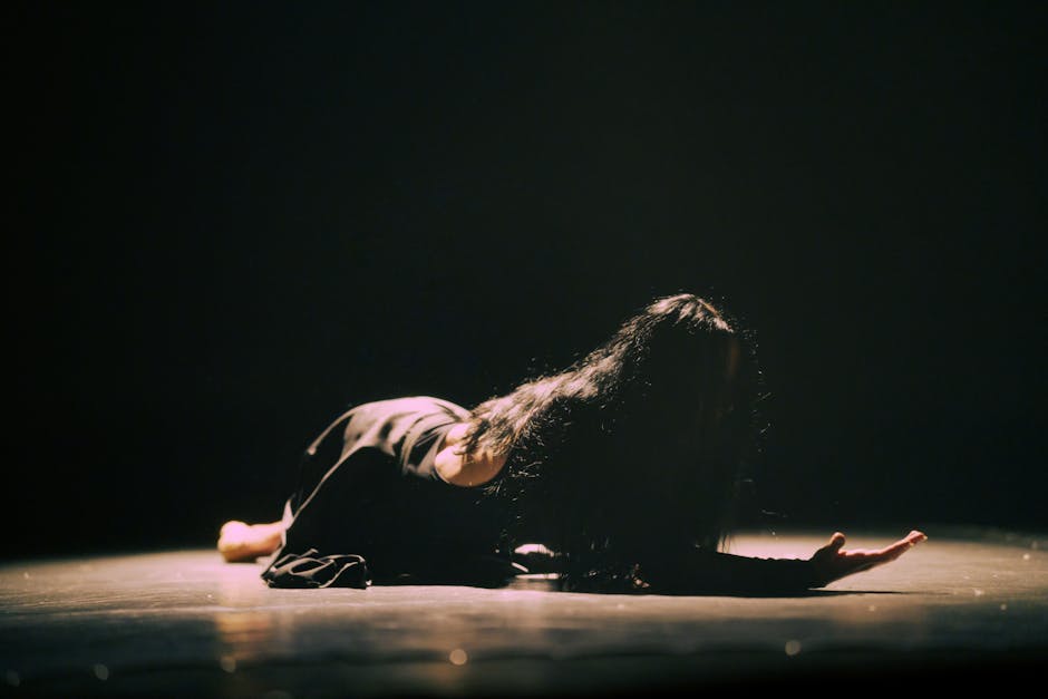 A woman in a dramatic dance performance, highlighting emotion and movement on stage.
