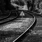 Interpretable Optimal Transport for Space Logistics Systems Monochrome photo of railway tracks with a triangular zero sign, set in natural surroundings.