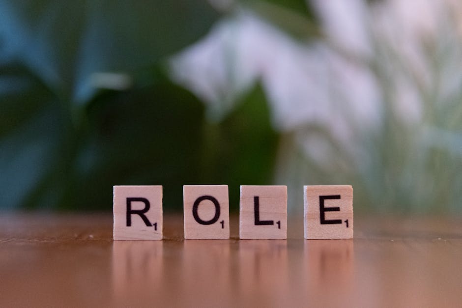 Close-up of Scrabble tiles spelling 'ROLE' on a wooden surface with a blurred background.