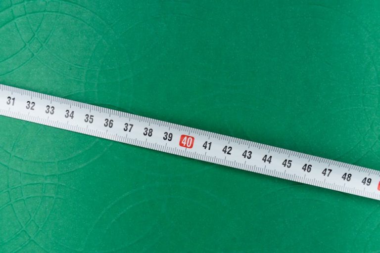 A measuring tape lying diagonally on a green textured surface.