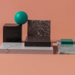 A minimalist geometric arrangement with various textured blocks and a sphere on a peach backdrop.