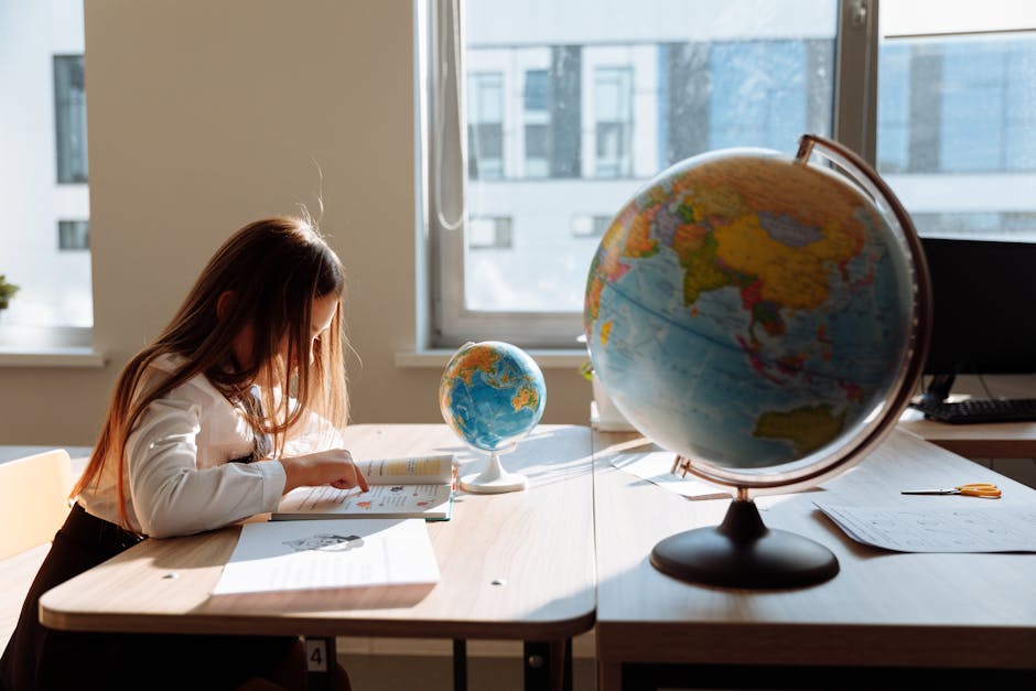A young girl diligently studying in a sunlit classroom with a globe and books.