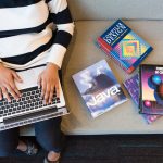 <h1>Meta-Learning Nano-Fabrication Compilers: The Future of Hardware-Level Cybersecurity</h1> Woman using laptop on sofa, surrounded by programming books, learning coding.