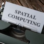A vintage typewriter with a paper displaying the text 'SPATIAL COMPUTING' on a wooden desk.