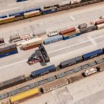 High angle drone shot of a logistics hub with stacked containers and a forklift.