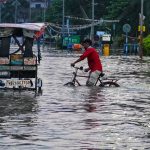 Multimodal Climate Adaptation Algorithms: Future of Resilient Ag Man with bicycle navigating flooded street in Kolkata's urban area, India.