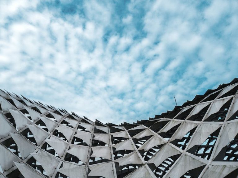 Dynamic view of a modern architectural structure against a cloudy blue sky.