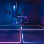 Open-World Metamaterial Simulators for Climate Tech Solutions Explore a cutting-edge VR gaming room featuring vibrant neon lights and advanced technology.