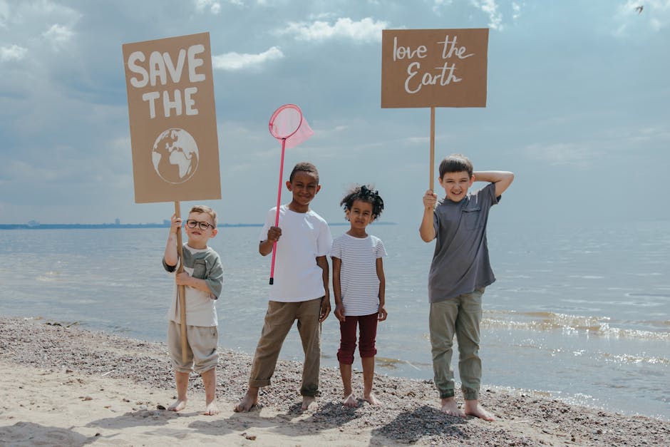 Group of children holding environmental signs on a beach promoting Earth protection.