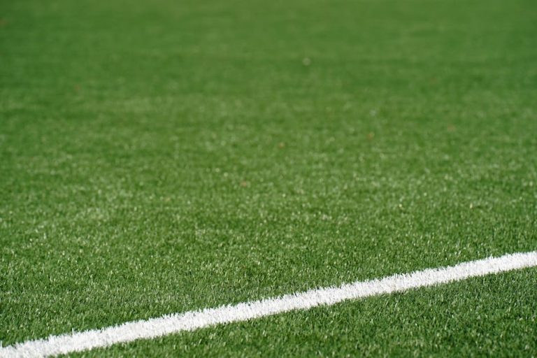 Close-up view of a green artificial soccer field with a white boundary line and space for text.