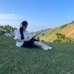 <h3>Outline</h3> Young woman reading in a tranquil grassy landscape, Cao Lộc, Vietnam.