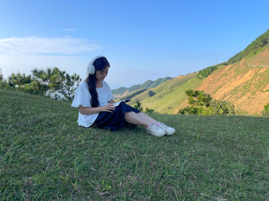 Young woman reading in a tranquil grassy landscape, Cao Lộc, Vietnam.