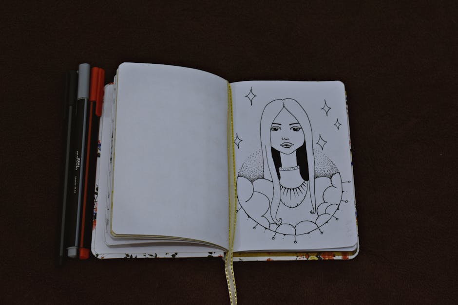 Artistic sketch of a woman in an open notebook with pens on a dark surface.