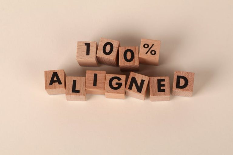 Wooden blocks spelling '100% Aligned' on a neutral background, conveying precision and alignment.