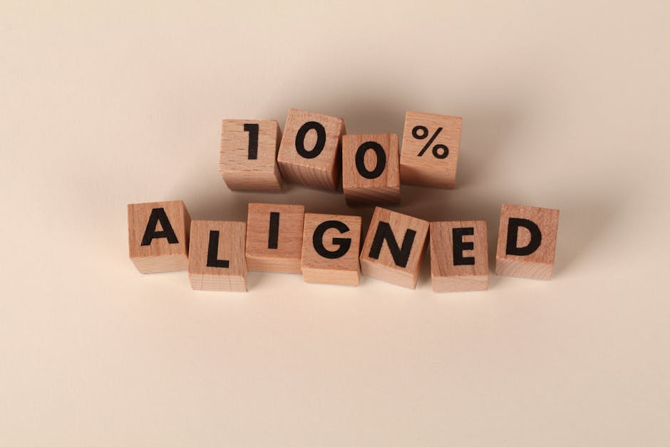 Wooden blocks spelling '100% Aligned' on a neutral background, conveying precision and alignment.