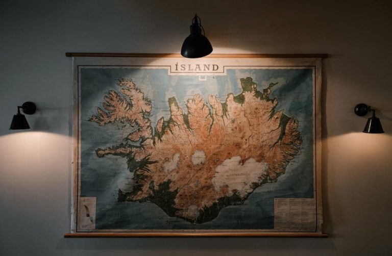 Shabby looking paper map of Iceland hung on wall and lit up with small lamps in darkened room of research station