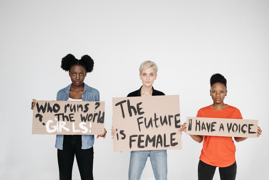 Three diverse women holding signs empowering female voices and rights.