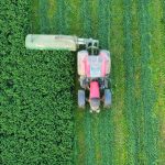 Precision Farming with Multimodal 2D Materials and Algorithms Aerial photo of a red tractor working in a green agricultural field, creating vibrant patterns.
