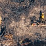 Aerial shot depicting heavy machinery in a deforested area, highlighting environmental impact.