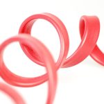 Close-up of a red rubber tube with elegant curves against a white background.