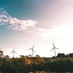 Quantum-Enhanced Carbon Removal: Neuroethics and Climate Tech Wind turbines in a lush landscape generating renewable energy under a bright sky.