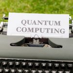 A typewriter with 'Quantum Computing' text outdoors on grass, blending old and new technologies.