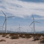 A scenic view of wind turbines in a desert, symbolizing clean, renewable energy technology.