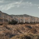 <h1>Resource-Constrained Climate Adaptation Standards for Distributed Ledgers</h1> Wind turbines generating clean energy in a mountainous desert landscape under a clear sky.