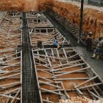 Construction workers at a site with wooden framework in progress, showcasing development.
