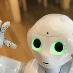 <h1>Risk-Sensitive Cellular Robotics: Bridging Cognitive Science and Autonomous Control</h1> A futuristic humanoid robot with glowing green eyes in a modern setting.
