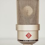 Close-up image of a vintage Neumann condenser microphone showcasing its metallic design.