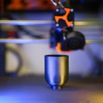 Innovative close-up of 3D printer crafting a metallic object, showcasing modern technology.